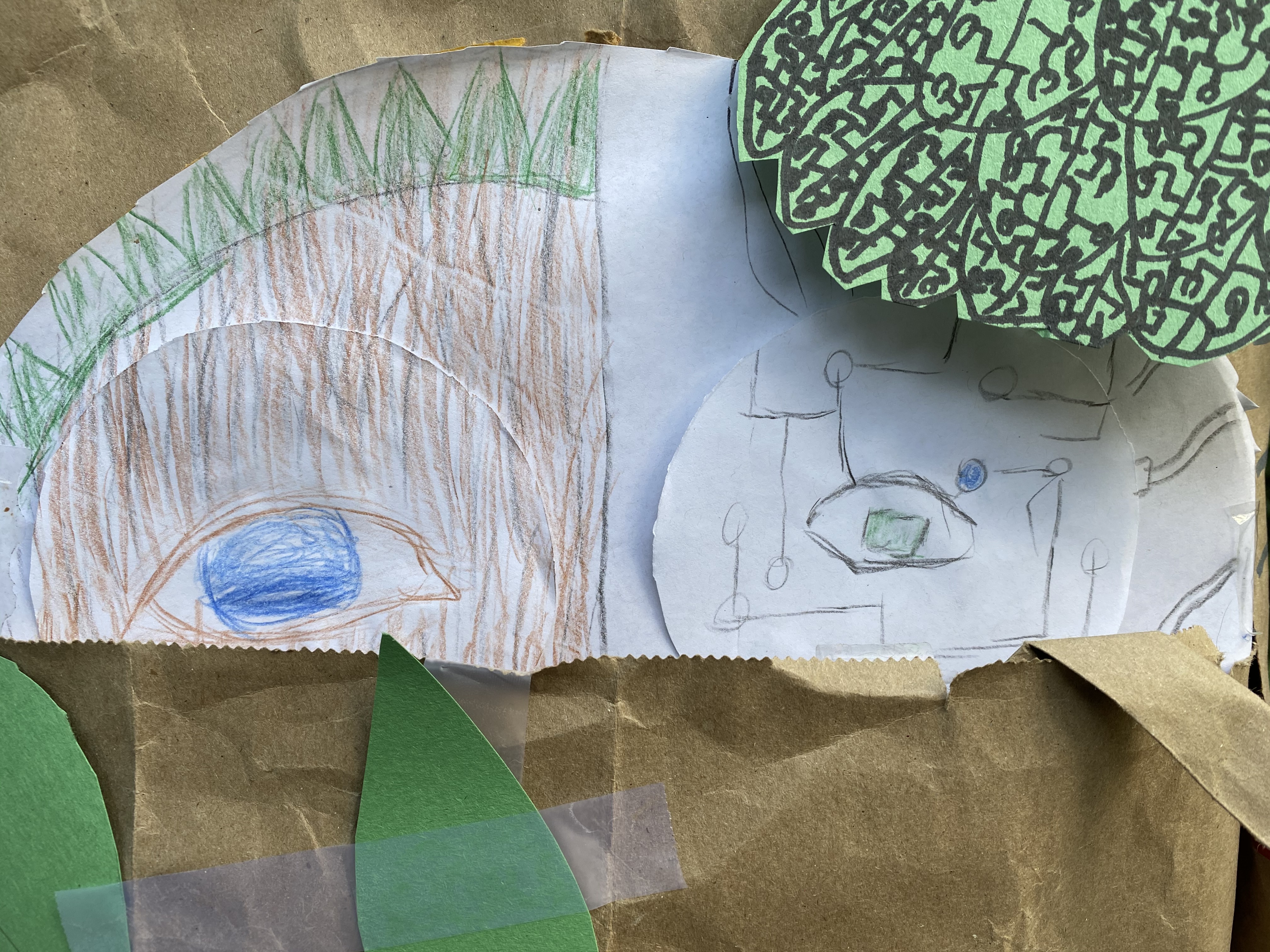 A children's craft project made out of a paperplate and brown paper. The paper plate has been divided in half. The left half contains the image of a face in the bark of a tree - this image represents nature. The right side of the drawing features the other side of the face, but this side is composed of microchips.